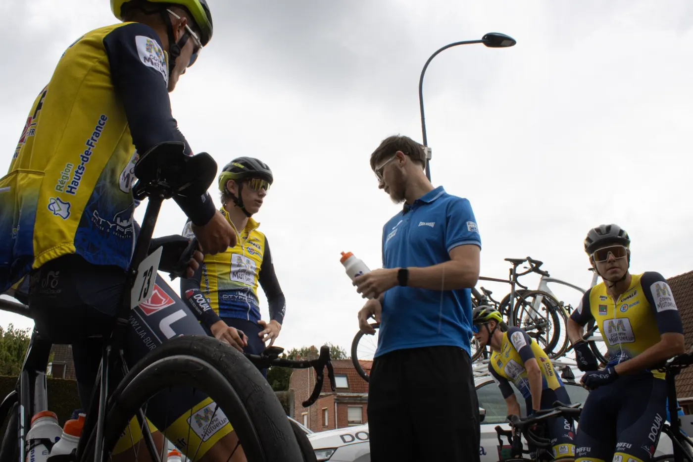 Lucas Plouvin tend un bidon à un coureur de l'ESEG Douai avant le départ